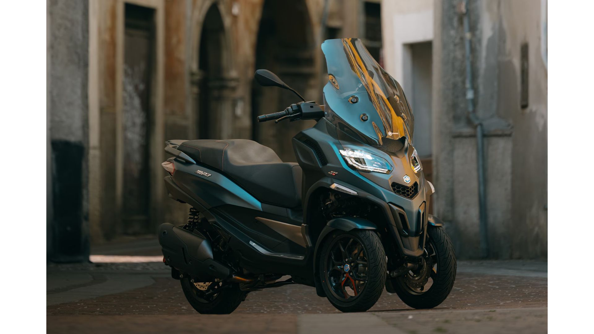 Piaggio MP3 530 HPE trikolesni skuter parkiran v mestu z visokim vetrobranskim steklom