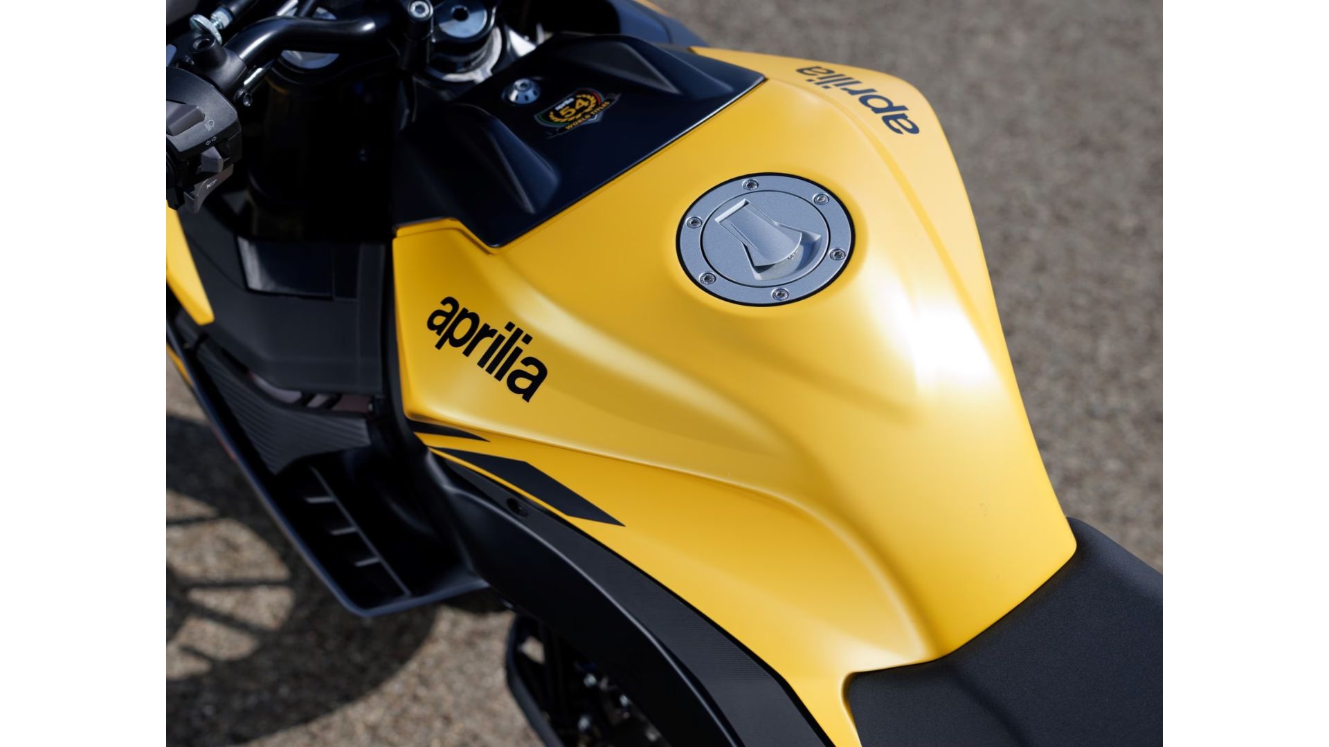 Rezervoar motocikla Aprilia Tuono 125 v rumeni barvi – detajl športnega dizajna in logotipa Aprilia