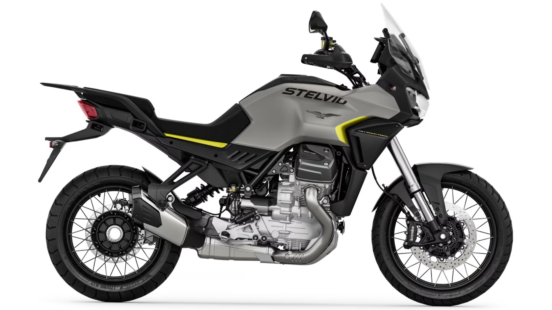 Avanturistični motocikel Moto Guzzi Stelvio v mat črno-sivi kombinaciji z rumenim detajlom, prikazan v levem bočnem profilu na belem ozadju.