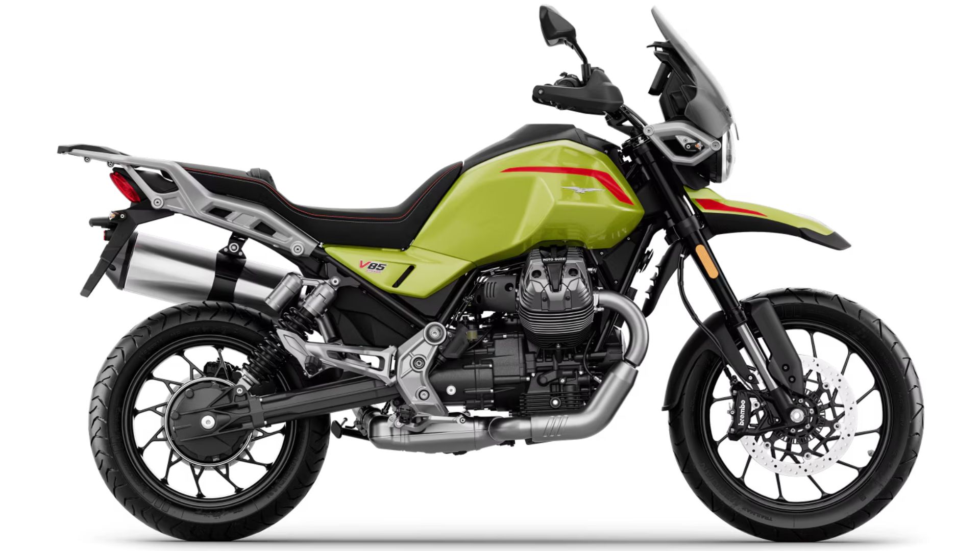Stranski profil motocikla Moto Guzzi V85 TT v sivi barvi z rdečim logotipom, dvema izpušnima cevema, prednjim in zadnjim diskovnim zavoram ter litimi platišči, na belem ozadju.