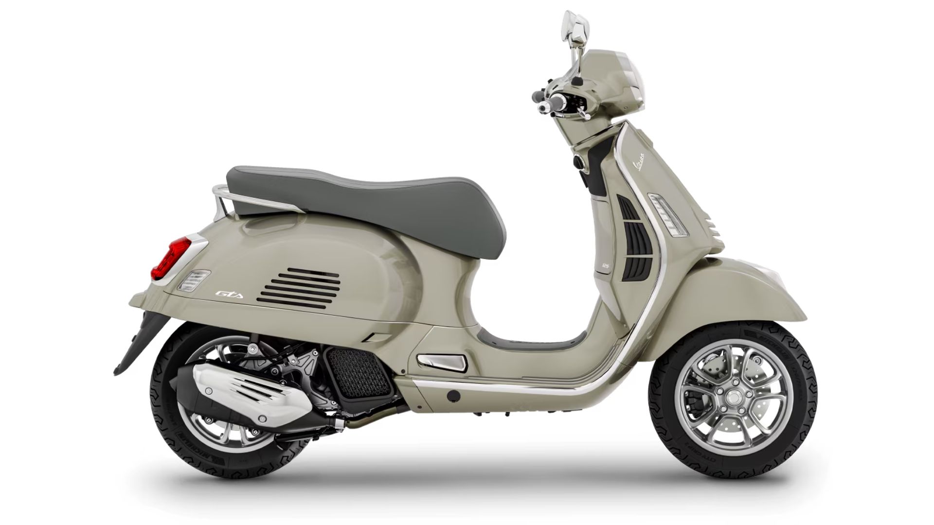 Stranski pogled na skuter Vespa v svetli bež barvi, ki prikazuje eleganten dizajn z udobnim sedežem in modernimi kolesi z litimi platišči.