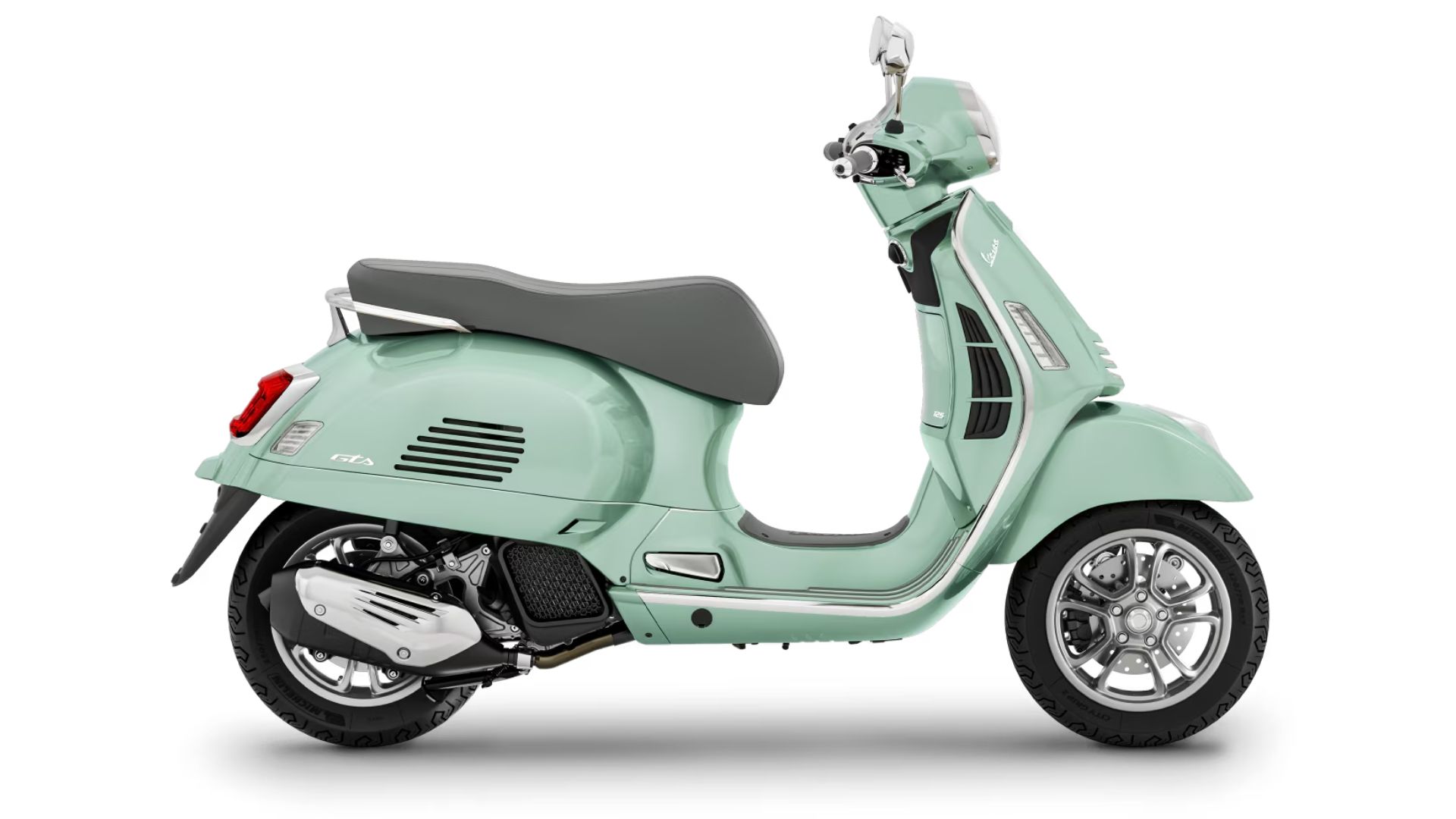 Stranski pogled na skuter Vespa v svetlo zeleni barvi, ki prikazuje eleganten dizajn z udobnim sedežem in modernimi kolesi z litimi platišči ter svetlimi detajli na telesu.