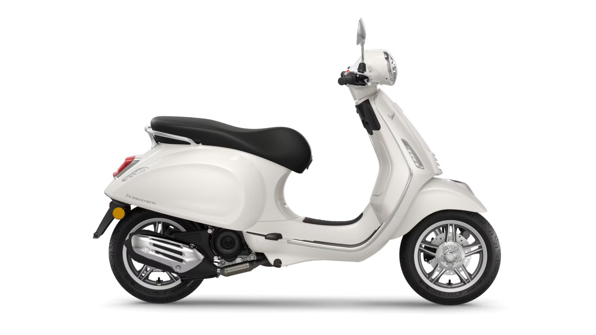 Stranski profil skuterja Vespa Primavera v biserno beli barvi s črnim sedežem in srebrnimi litimi platišči, na belem ozadju.