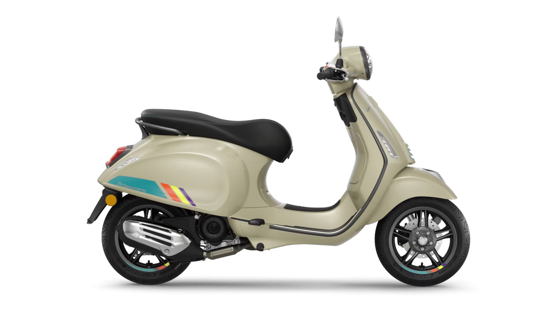 Stranski profil skuterja Vespa Primavera v peščeno-bež barvi z črnim sedežem, barvnimi grafičnimi črtami na boku in litimi platišči, na belem ozadju.