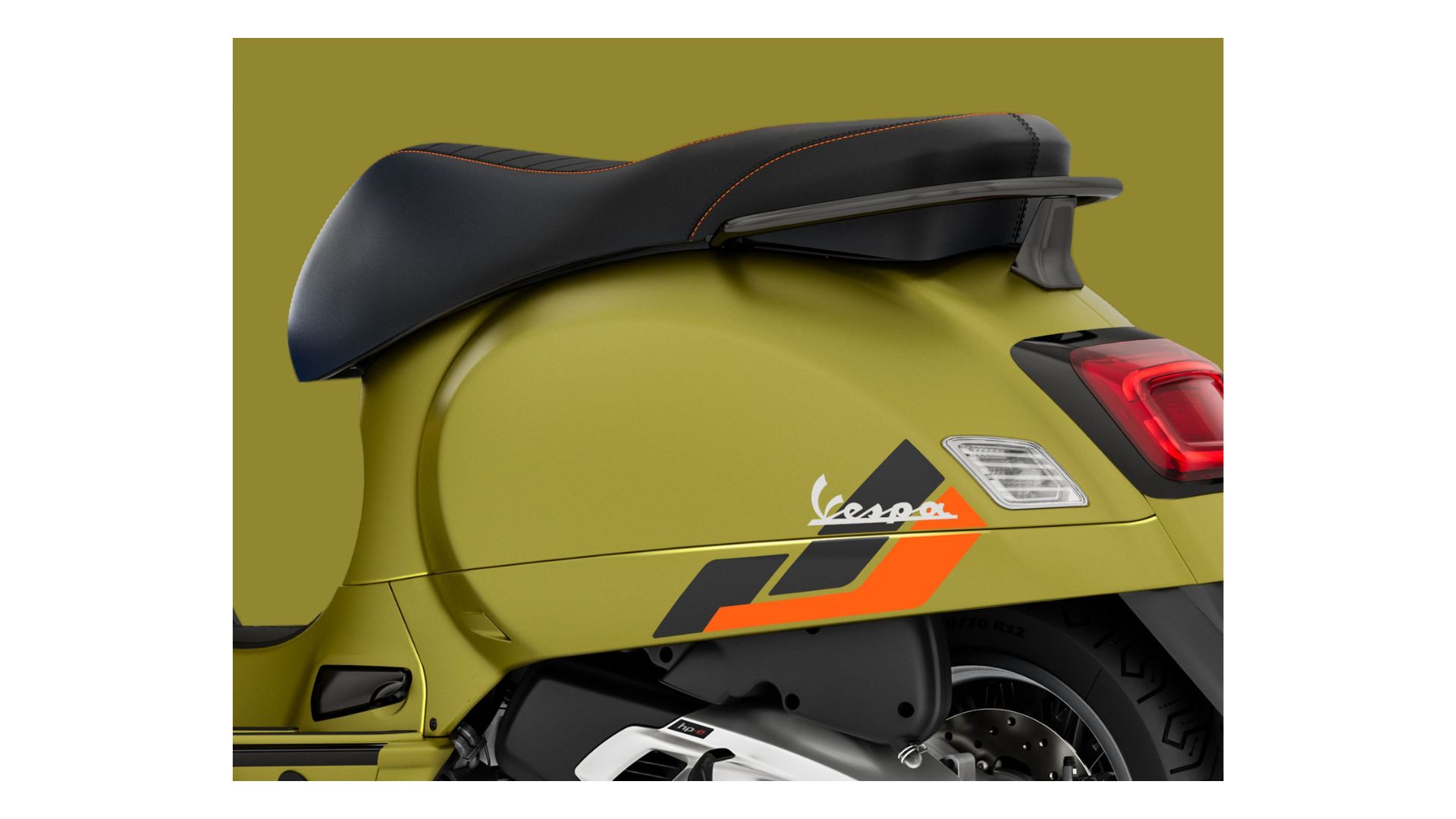 A detailed view of the rear section of the scooter, showcasing the smooth bodywork, the black seat with orange stitching, and the Vespa logo. The color and sporty decals along the side further highlight its modern appeal.