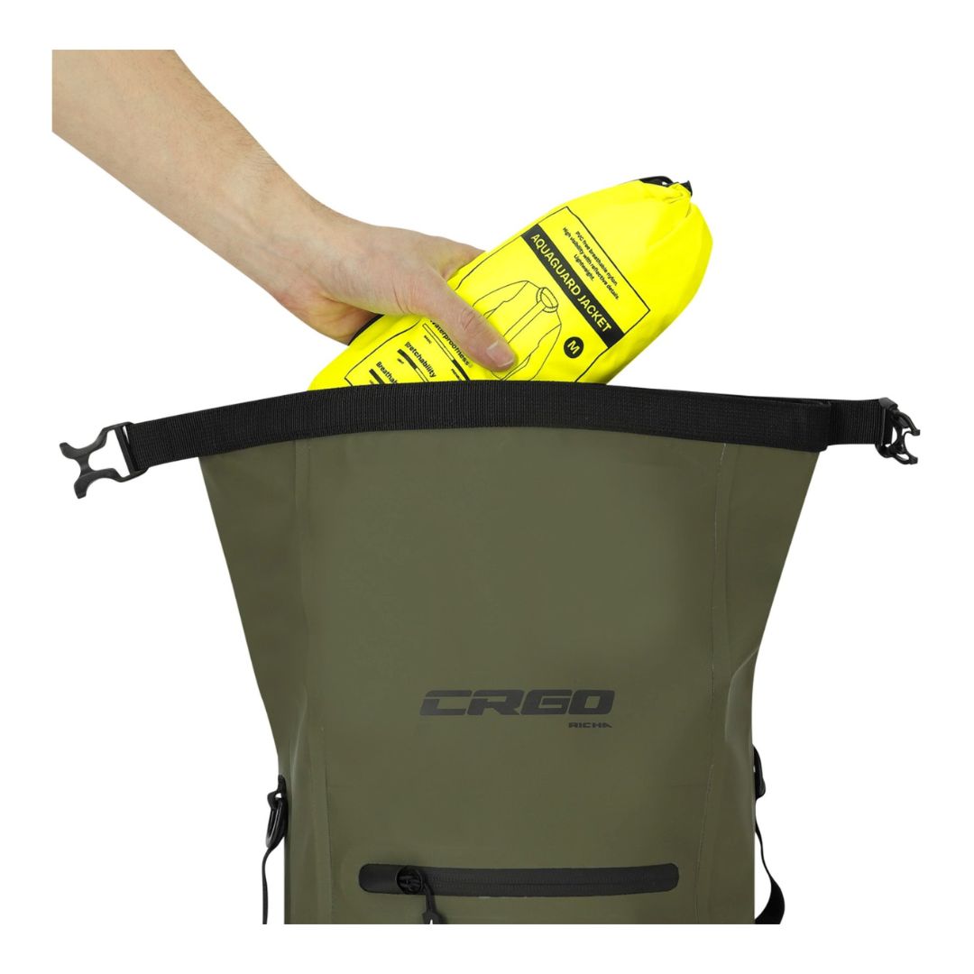 Zgornji del odprtega nahrbtnika z roll-top zapiranjem; roka vstavi rumeno nepremočljivo vrečo v notranjost.
